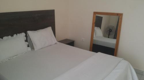 um quarto com uma cama branca e um espelho em PagersHome Suites - Classic Nyarutarama em Kigali