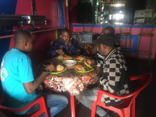 un grupo de hombres sentados en una mesa comiendo comida en PagersHome Suites - Classic Nyarutarama, en Kigali