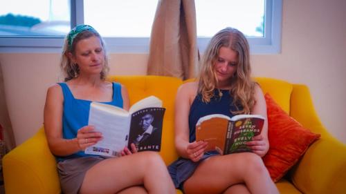 zwei Frauen, die auf einer Couch sitzen und Bücher lesen in der Unterkunft Hotel Posada Stella Maris in Puerto Barrios