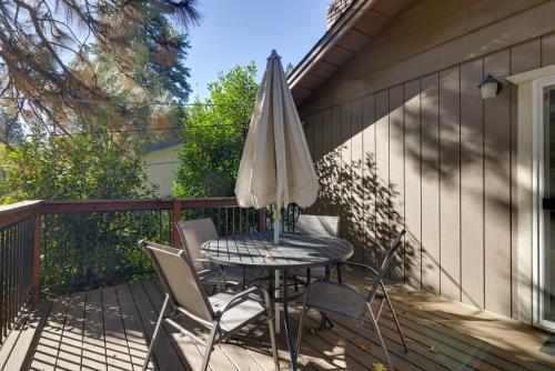 a table and chairs with an umbrella on a deck at Furnished Deck and Fire Pit Sherwood Forest Cabin in Twain Harte