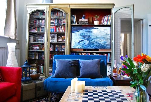 ein Wohnzimmer mit einer blauen Couch und einem Bücherregal in der Unterkunft Hampton Court Snug Sleeps 6 - 5min Walk to Palace and Train in East Molesey