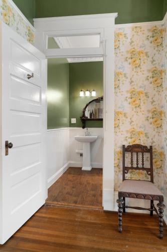 a bathroom with a sink and a door with a chair at Ross Mansion Bed & Breakfast in Hattiesburg
