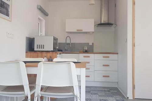 cocina con sillas blancas y mesa de madera en Come à la maison!, en Coupvray