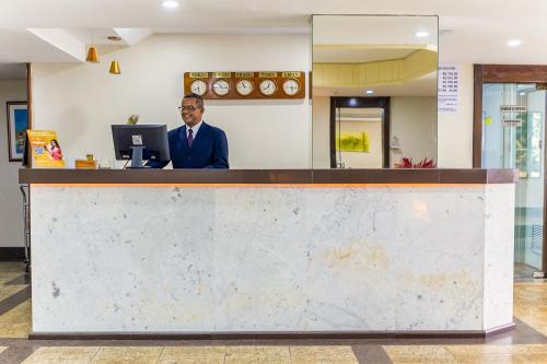 a man sitting at a counter in a lobby at Hotel Golden Park Rio de Janeiro Aeroporto By Nacional Inn in Rio de Janeiro