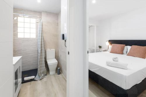 ein Schlafzimmer mit einem weißen Bett und ein Badezimmer in der Unterkunft Refugio playero para 5 personas in Castelldefels