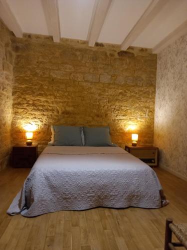 een slaapkamer met een groot bed met 2 lampen bij Maison de la Ruelle, vue sur les toits de Domme in Domme