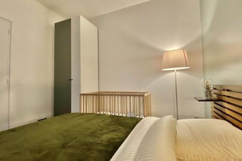 a bedroom with a bed with a lamp and a green blanket at Charmant appartement à Nogent-sur-Marne in Nogent-sur-Marne