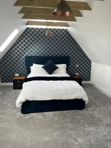 a bedroom with a large bed with a blue headboard at The Hayloft in Hernhill