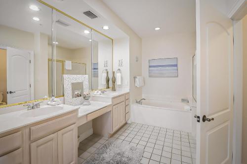 ein Badezimmer mit zwei Waschbecken, einer Badewanne und einer Dusche in der Unterkunft Desoto 305 Seaside Bliss in Tybee Island