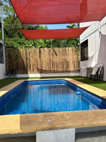 una piscina en un patio trasero con una sombrilla roja en Departamento Amueblado con Alberca Pedregal A, en Tamasopo