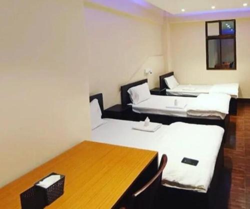Habitación con 2 camas y mesa de madera. en OYO Flagship The Thangal Hotel en Imphal