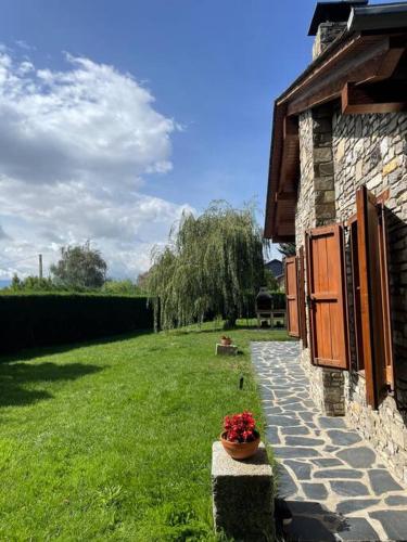 a stone building with a potted plant next to a yard at Cal Fray, San Martí d'Aravó, Puigcerdà in Guils de Cerdaña