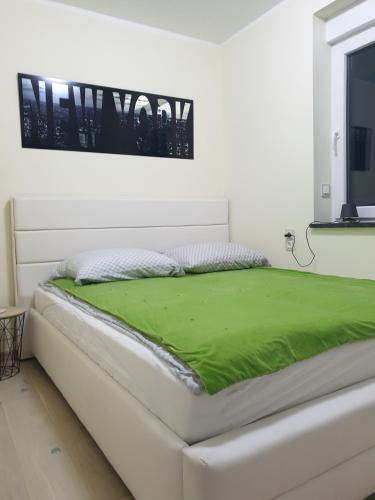 - un lit blanc avec une couverture verte dans l'établissement ApartLili 2, à Polanica-Zdrój