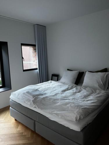 a bedroom with a large bed with white sheets and pillows at Boutique City Apartment Aarhus in Aarhus