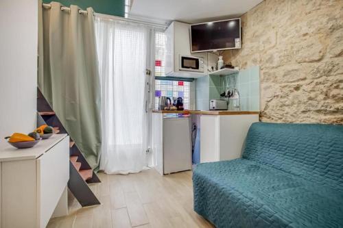 un salon avec un canapé bleu et une cuisine dans l'établissement Tiny boutique studio in Paris 11, à Paris