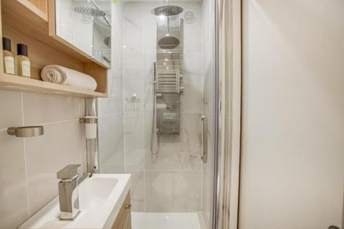 une salle de bain blanche avec une douche et un lavabo dans l'établissement Tiny boutique studio in Paris 11, à Paris