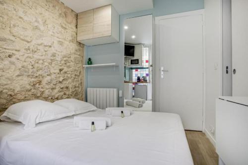 - un lit blanc dans une chambre dotée d'un mur en pierre dans l'établissement Tiny boutique studio in Paris 11, à Paris