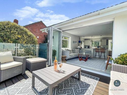 a patio with a table and a living room at Seafeathers - Luxury Holiday Home with Sea Views in Overcombe