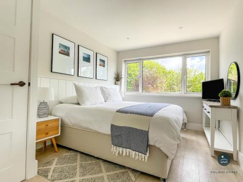 a bedroom with a bed and a desk and a window at Seafeathers - Luxury Holiday Home with Sea Views in Overcombe