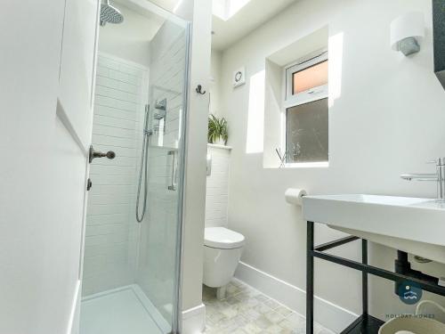 a white bathroom with a shower and a sink at Seafeathers - Luxury Holiday Home with Sea Views in Overcombe