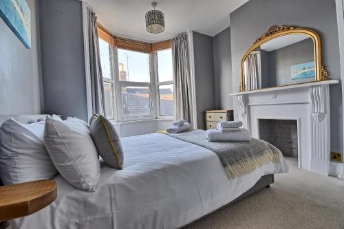 a bedroom with a white bed and a mirror at Sunnyside - Stylish dog friendly harbour views in Weymouth