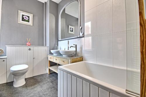 uma casa de banho com uma banheira, um WC e um lavatório. em Sunnyside - Stylish dog friendly harbour views em Weymouth