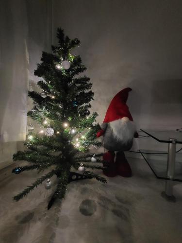 a santa claus sitting next to a christmas tree at City Home Taimi in Rovaniemi