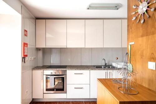 cocina con armarios blancos, fregadero y horno en Casa da Eira, en Tondela