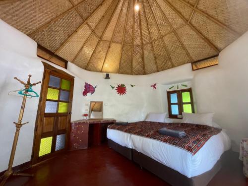 a bedroom with a bed with a thatched roof at Chiang Dao Roundhouses in Chiang Dao