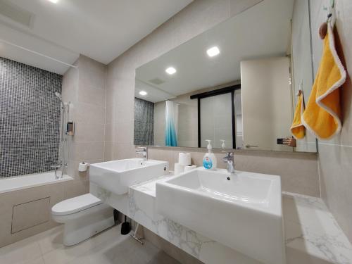 een badkamer met 2 wastafels, een toilet en een spiegel bij The Ooak Suites @ 163 Building (Mont Kiara) in Kuala Lumpur