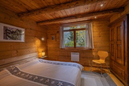 um quarto num chalé de madeira com uma cama e uma cadeira em Chalet Les Rindes em Nendaz