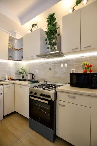 a kitchen with white cabinets and a stove top oven at Apartament Beauty Smarald by Cosmopolis in Ştefăneştii de Jos