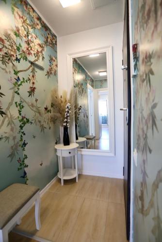 a hallway with a mirror and flowers on the wall at Apartament Beauty Smarald by Cosmopolis in Ştefăneştii de Jos