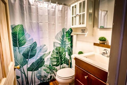 a bathroom with a toilet and a shower curtain with leaves at 5 bdrm Creekside Chalet located near 4 ski resorts in Weston