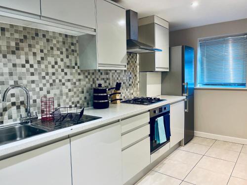 a kitchen with white cabinets and a sink at Absolutely Beautiful Hemel Hempstead 2-bedroom for 1-5 Guests - contractors welcome in Hemel Hempstead