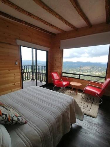 um quarto com uma cama e 2 cadeiras vermelhas em Mountain Glamping - Nature and Relax em Fúquene