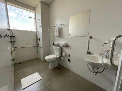 a bathroom with a toilet and a sink and a mirror at Transamerica Executive Maringá in Maringá