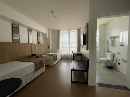 a hotel room with two beds and a bathroom at Transamerica Executive Maringá in Maringá