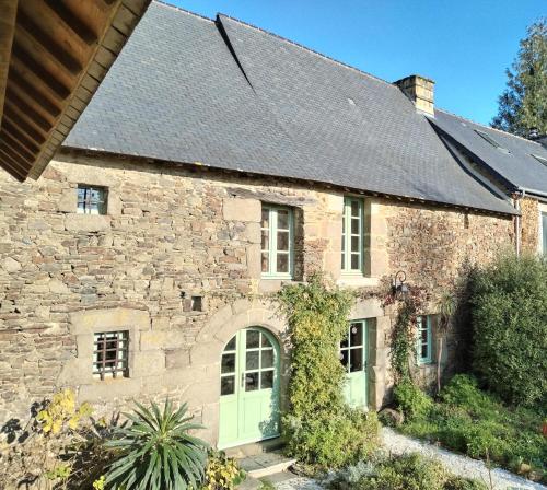 une vieille maison en pierre avec des portes vertes dans l'établissement La parenthèse verte, à Meillac