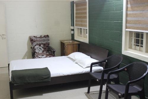 a small bedroom with a bed and two chairs at San Unik Homestay in Nilambūr