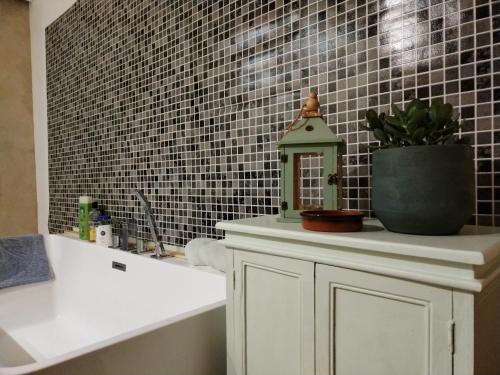 La salle de bains est pourvue d'une armoire blanche et d'un mur en carrelage. dans l'établissement La parenthèse verte, à Meillac