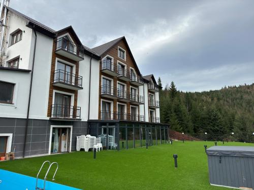 a large building with a green lawn in front of it at Konopka Forest Home & SPA in Bukovel