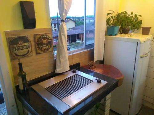 a kitchen with a barbecue grill and a window at Apartamento em Itanhaém com 2 quartos, Piscina e Ampla Varanda Gourmet in Itanhaém
