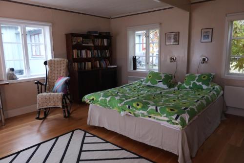 a bedroom with a bed and a chair and windows at Remarkable Harbour View Cabin. in Östhammar