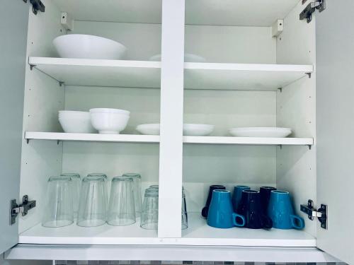 a cabinet filled with bowls and utensils at Absolutely Beautiful Hemel Hempstead 2-bedroom for 1-5 Guests - contractors welcome in Hemel Hempstead