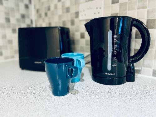 three blue cups sitting on a counter next to a coffee pot at Absolutely Beautiful Hemel Hempstead 2-bedroom for 1-5 Guests - contractors welcome in Hemel Hempstead