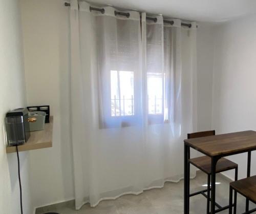 ベナルップ・カサス・ビエハスにあるSuites Benalup Centroの白いカーテン、テーブル、窓が備わる客室です。