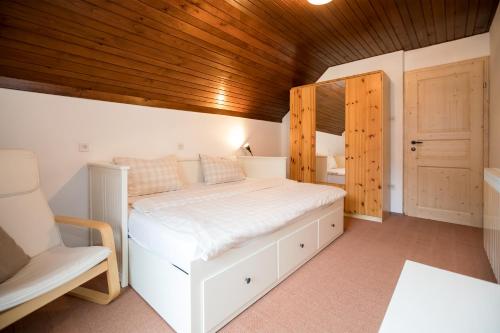 een slaapkamer met een wit bed en een houten plafond bij Apartma Hkavc Markež in Bohinj