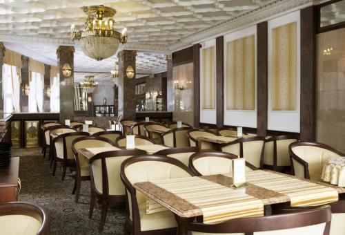a restaurant with tables and chairs and a chandelier at OREA Spa Hotel Palace Zvon Mariánské Lázně in Mariánské Lázně