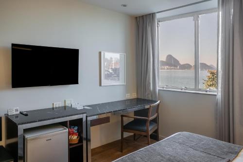 a hotel room with a desk and a tv at Orla Copacabana Hotel in Rio de Janeiro